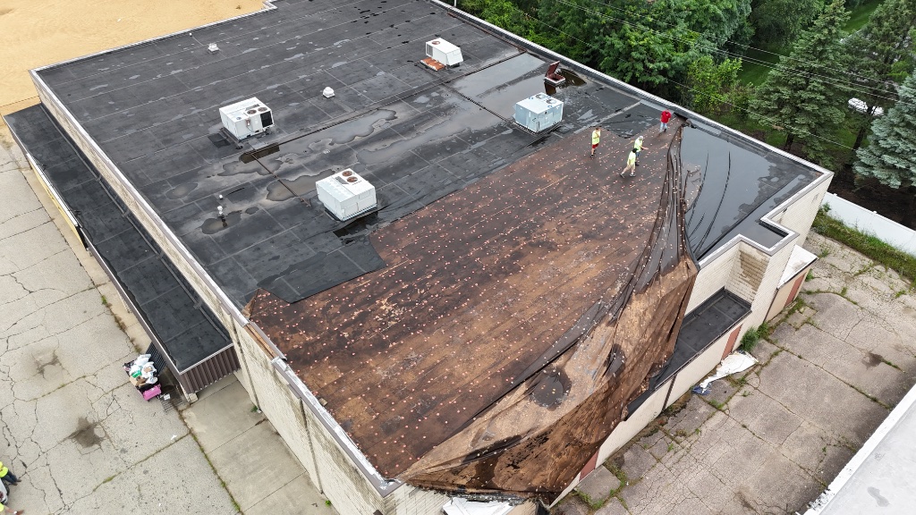 Storm-damaged commercial flat roof — membrane torn loose