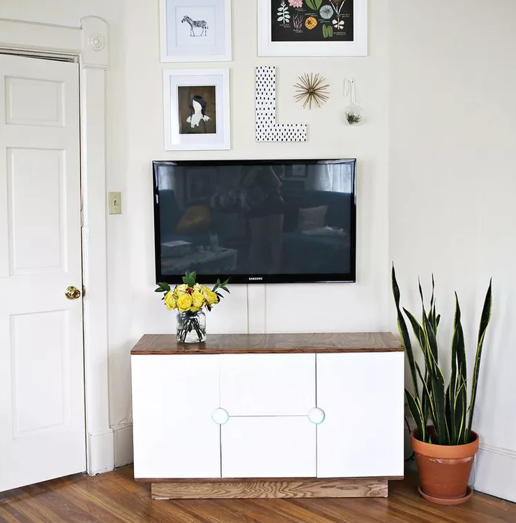 TV mounted on wall above media console with gallery wall