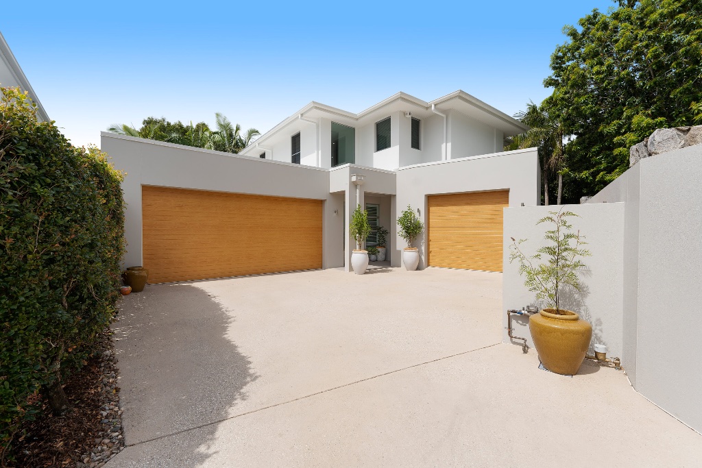 Resort residence — white rendered facade with timber garage doors