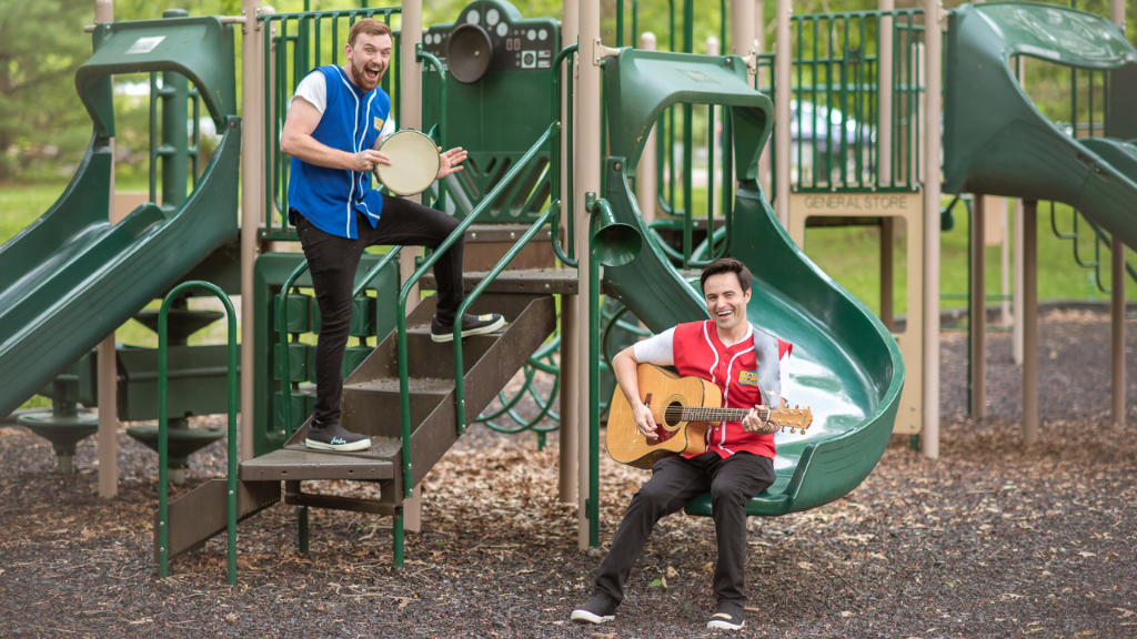 Vinnie and Jordan of the Good News Guys on a playground with a tambourine and guitar