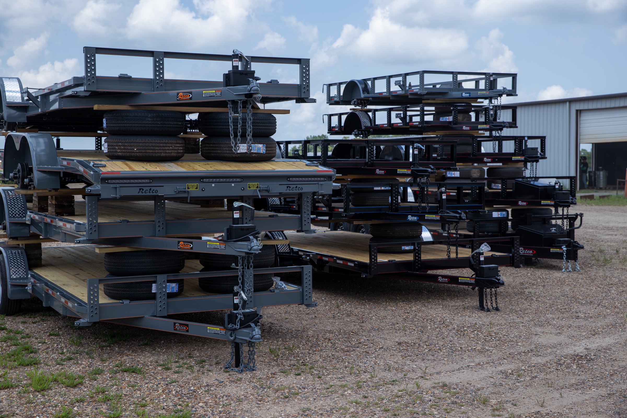 Stacked gray and black Retco utility trailers in inventory on the Retco lot