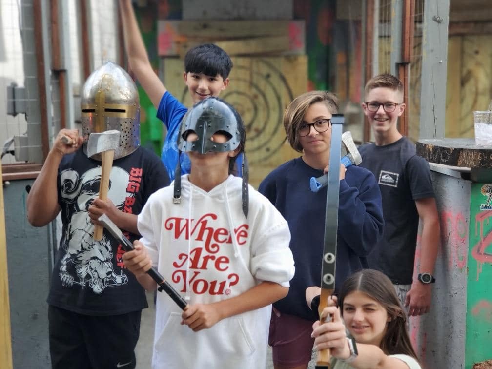 Group of friends in helmets posing with axes at Viking Axe Throwing