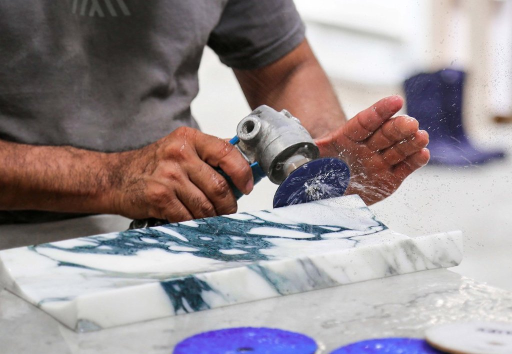 Artesano puliendo mármol arabescato — detalle de fabricación Marmi Signature