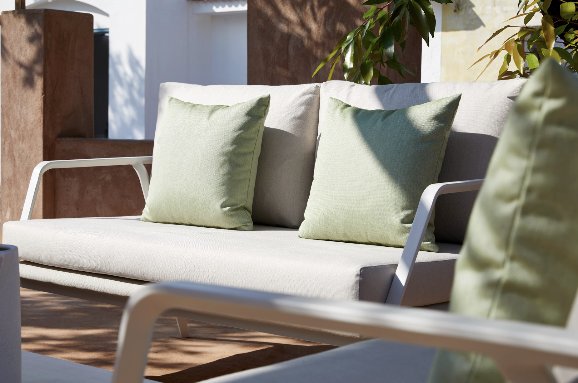 Sofá Samba en terraza con muros de terracota y vegetación al atardecer