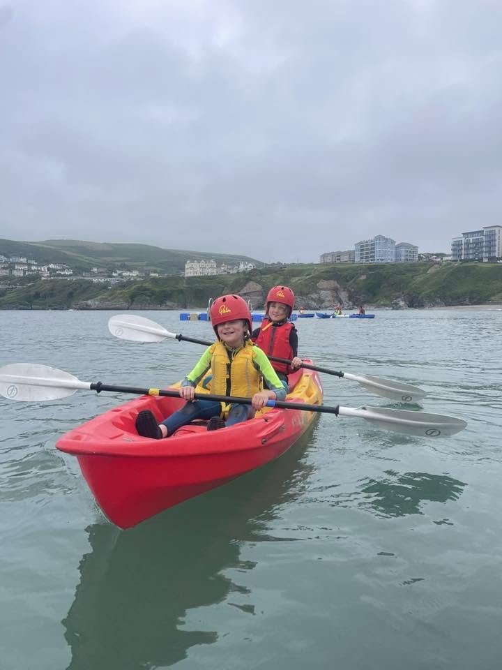 Two children kayaking in a red kayak