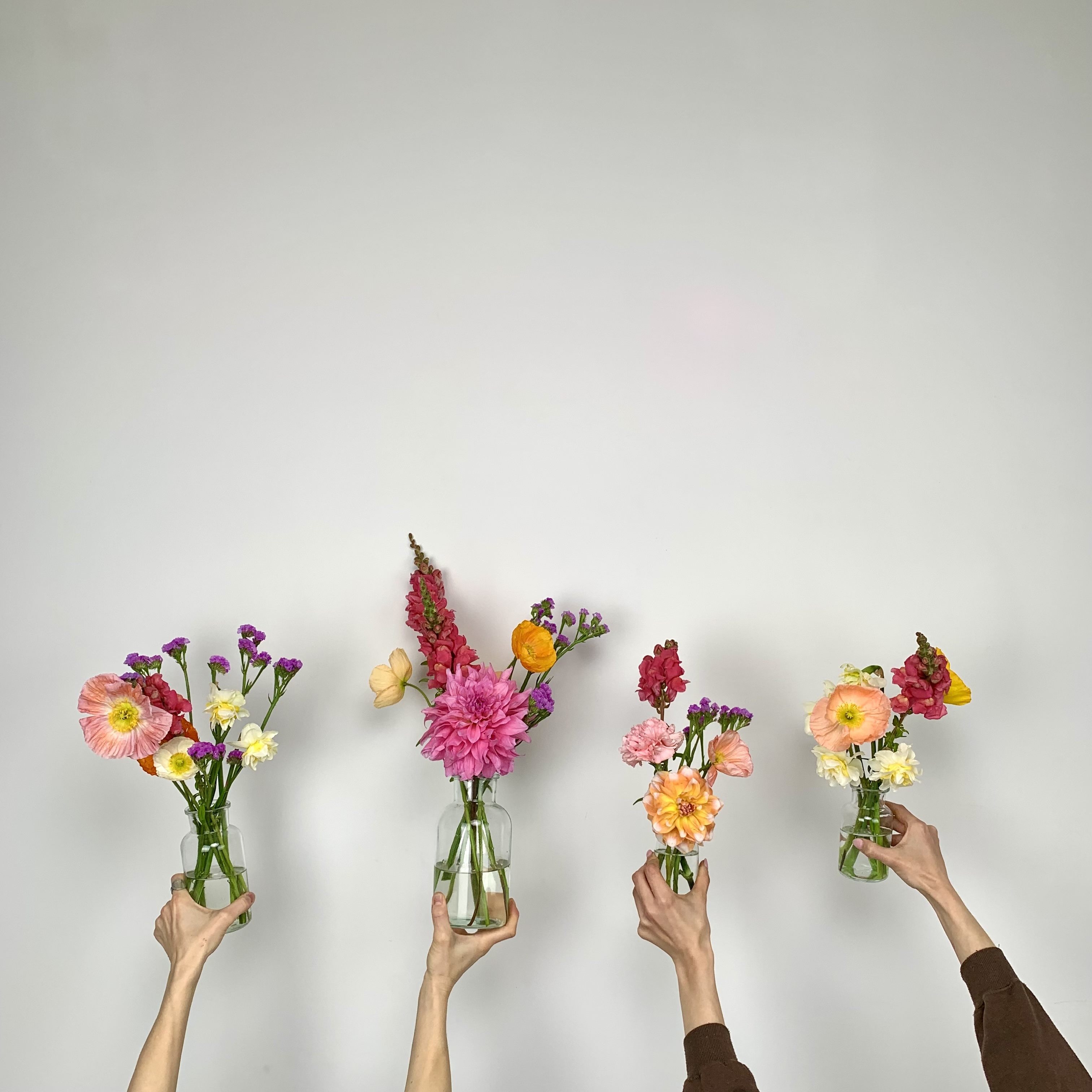 Hands holding small clear glass vases of delivered event flowers