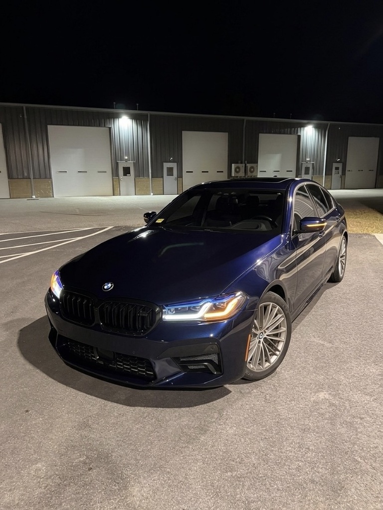 BMW 5 Series sedan with factory navy blue paint, photographed at night in front of a warehouse in Rhode Island, before a vehicle wrap by Xtreme Graphics Design.