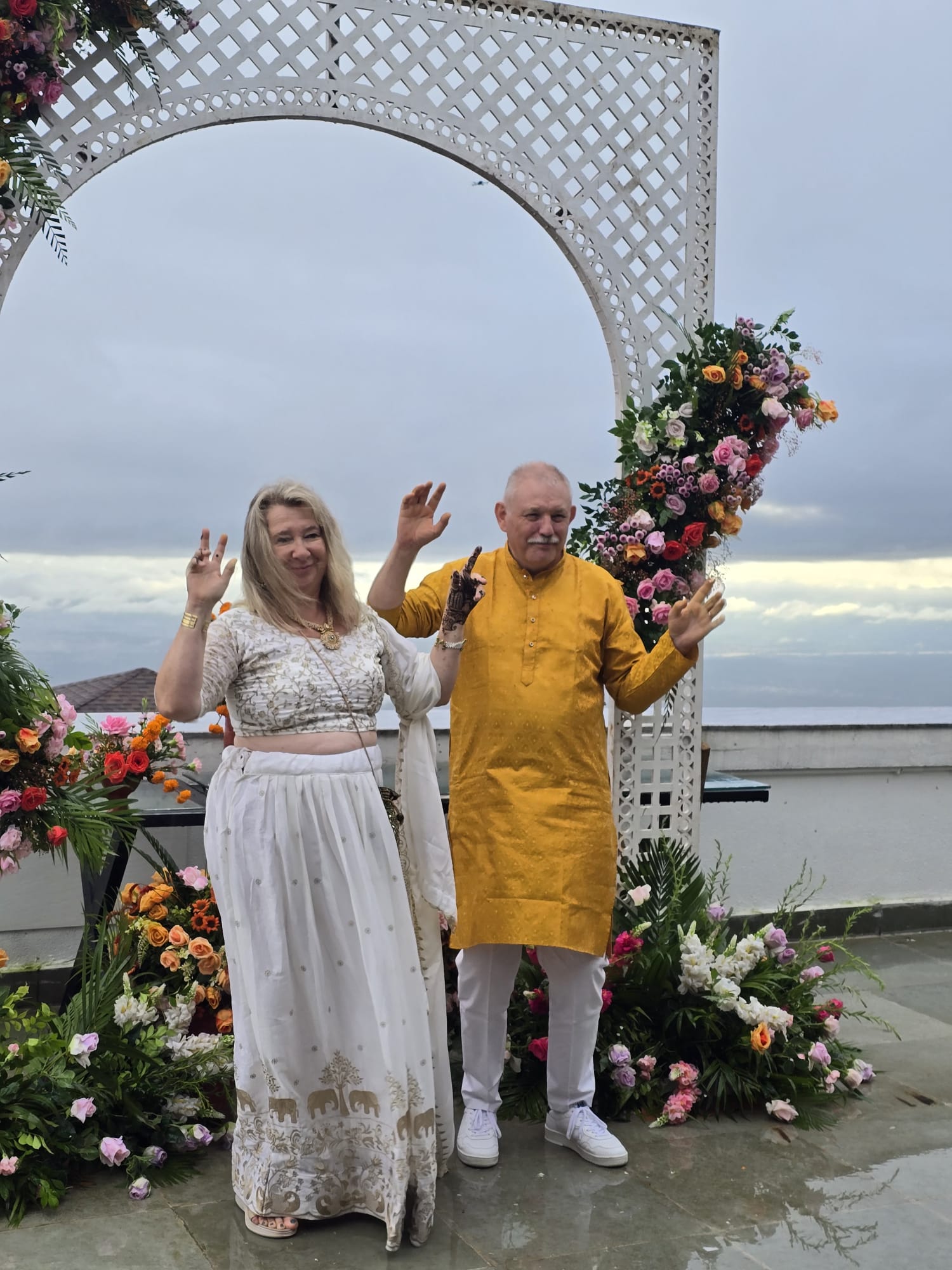 Monica and Romain posing under a floral archway