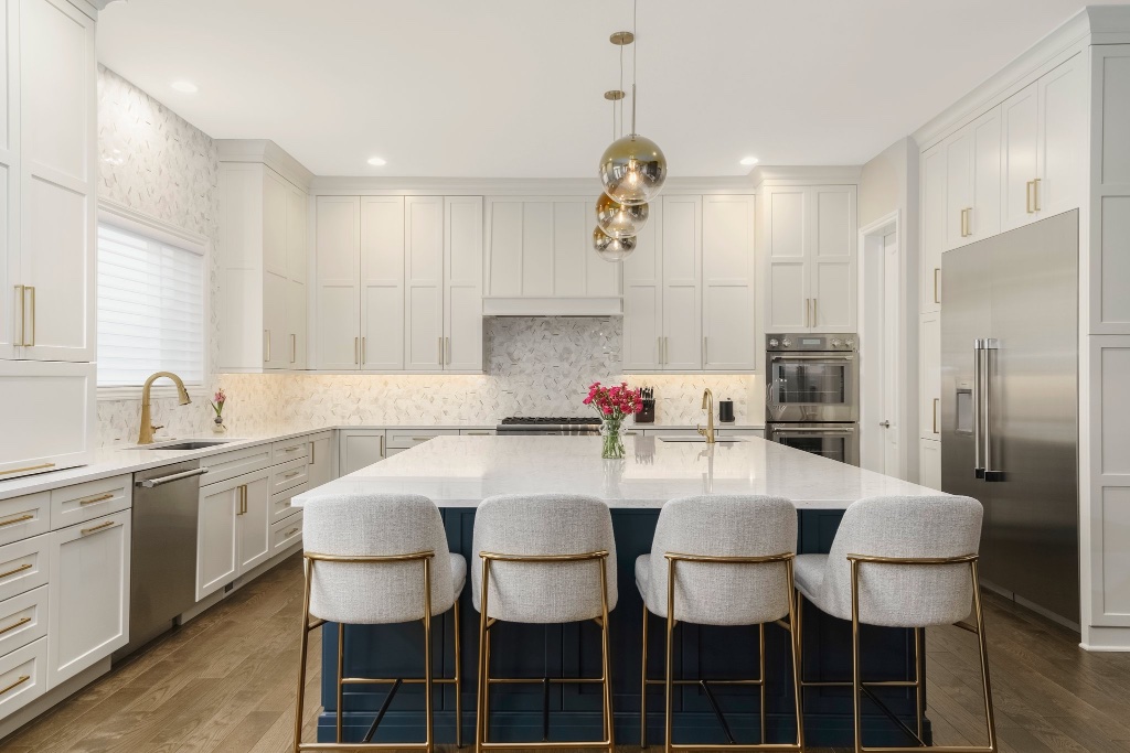 Sophisticated kitchen with navy blue island, white marble countertops, and brass fixtures