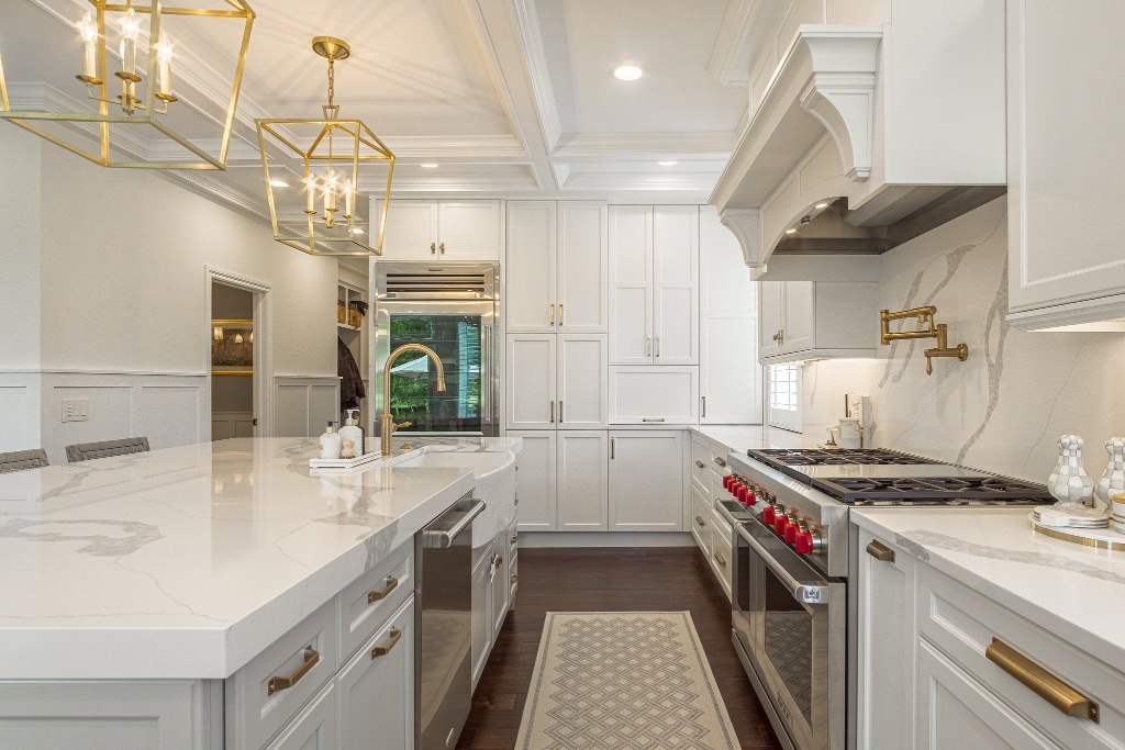 Modern kitchen with white shaker cabinetry, marble countertops, and brass fixtures
