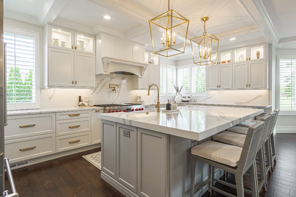 Modern kitchen with white shaker cabinetry, marble countertops, and brass fixtures