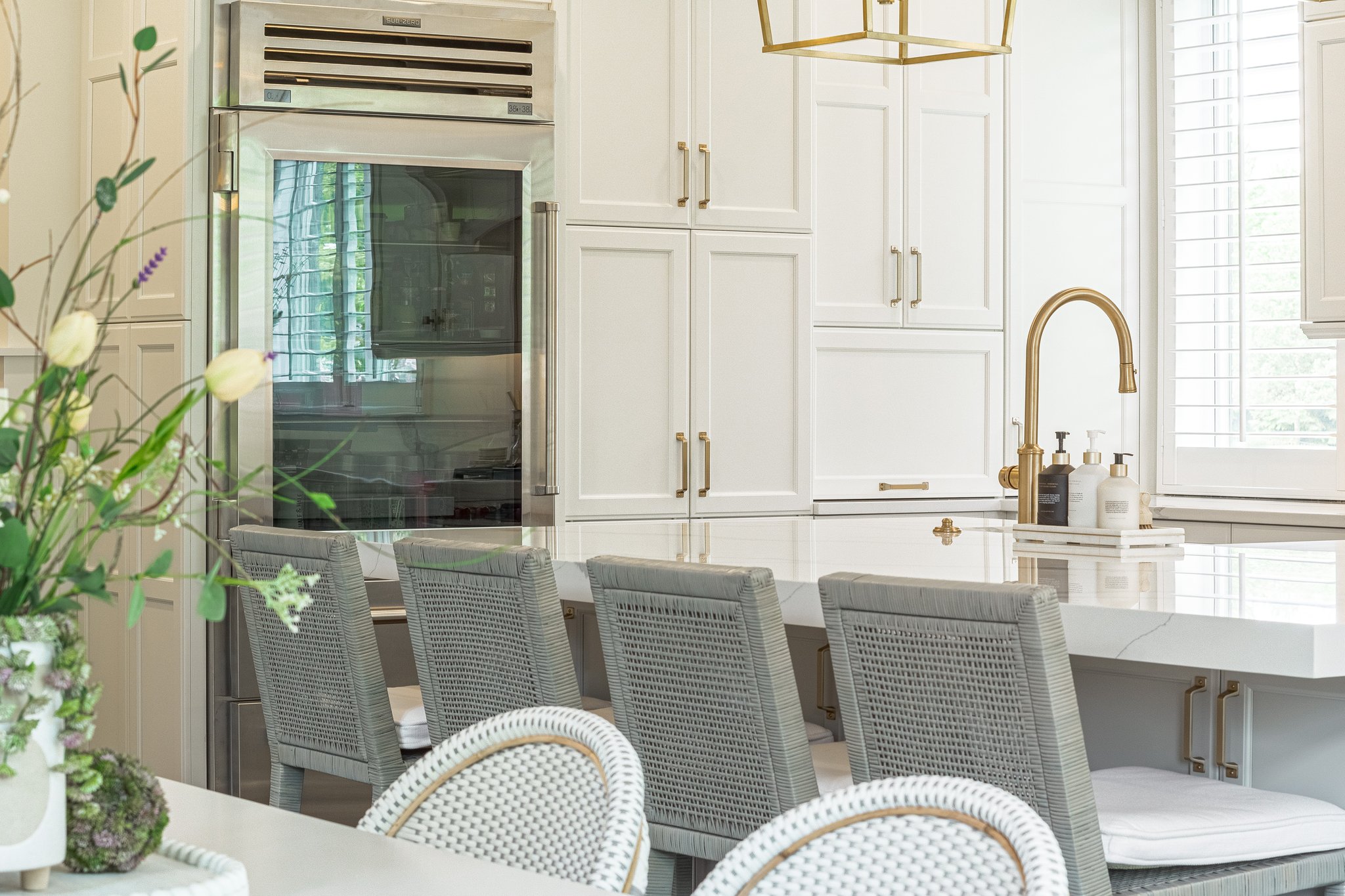 Modern kitchen with white shaker cabinetry, marble countertops, and brass fixtures