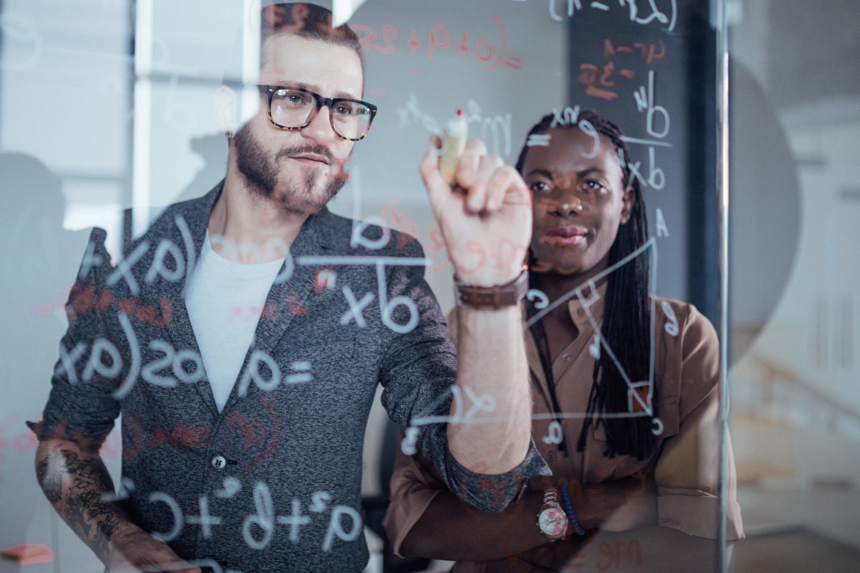 Two professionals collaborating on AI and data strategy in front of a glass whiteboard