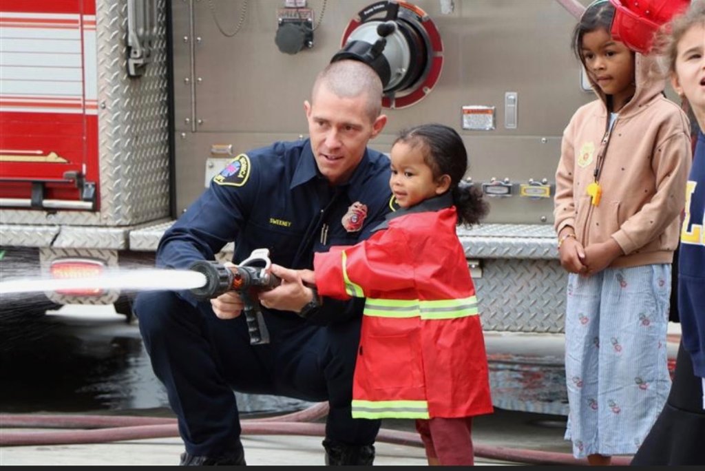 Firefighter helping child with hose at community event