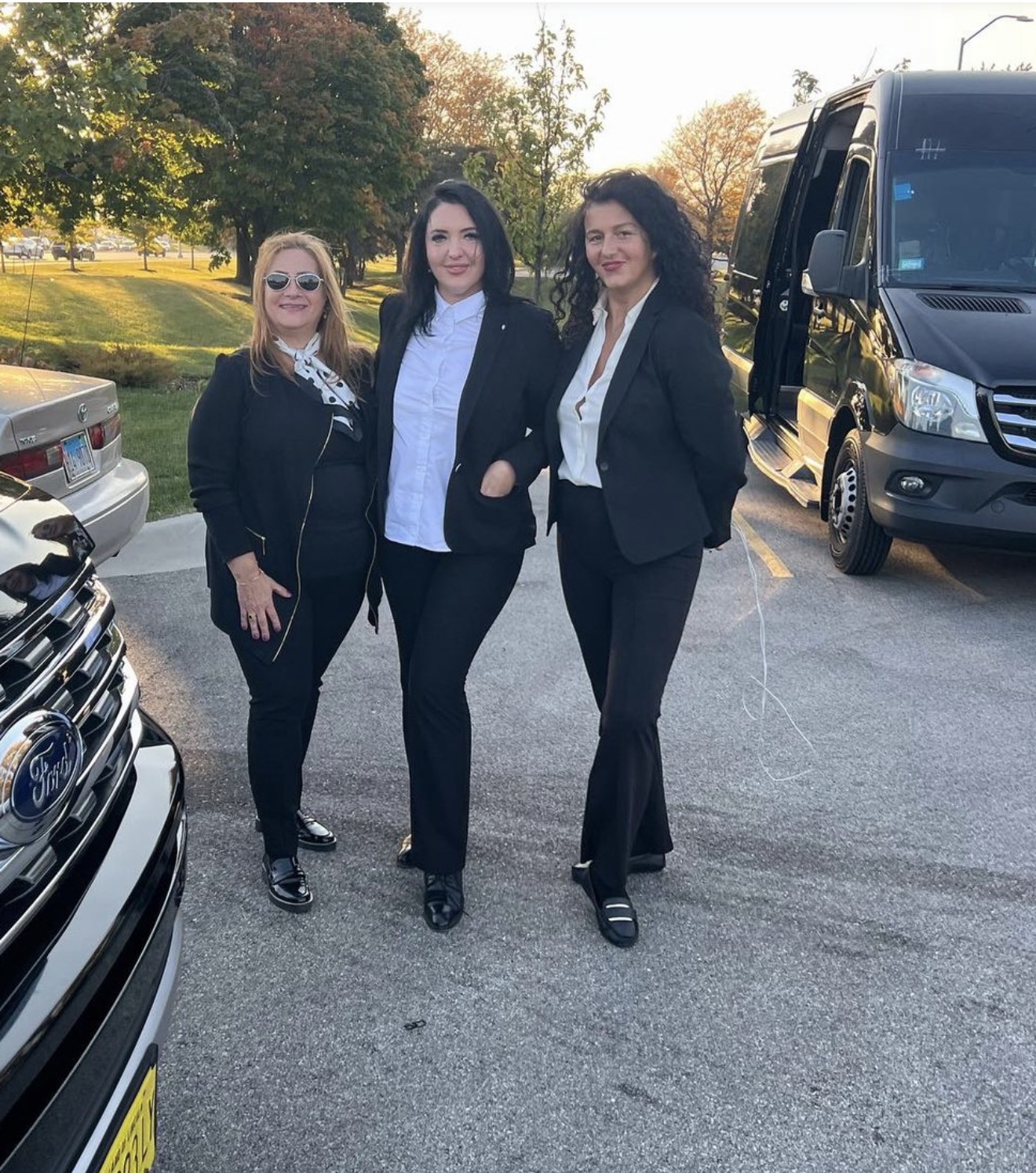 LivryLink female chauffeurs in professional black suits beside a luxury Sprinter