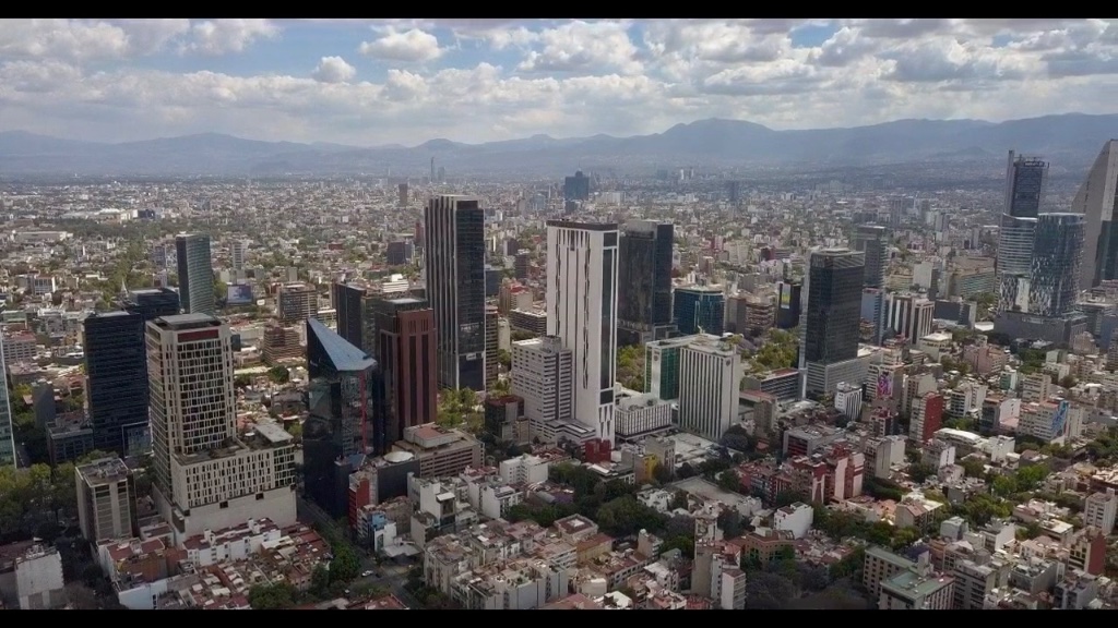 Vista aérea de la zona metropolitana de la Ciudad de México con rascacielos y montañas al fondo