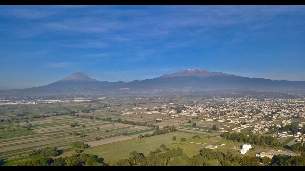 Vista aérea de los volcanes Popocatépetl e Iztaccíhuatl con campos agrícolas al frente