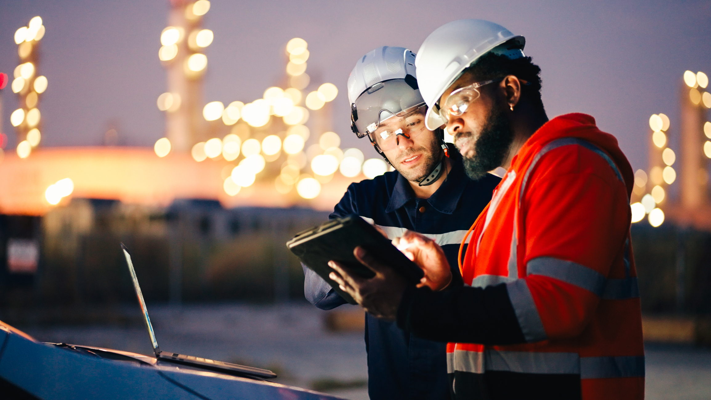 Two industrial workers reviewing information together on a tablet