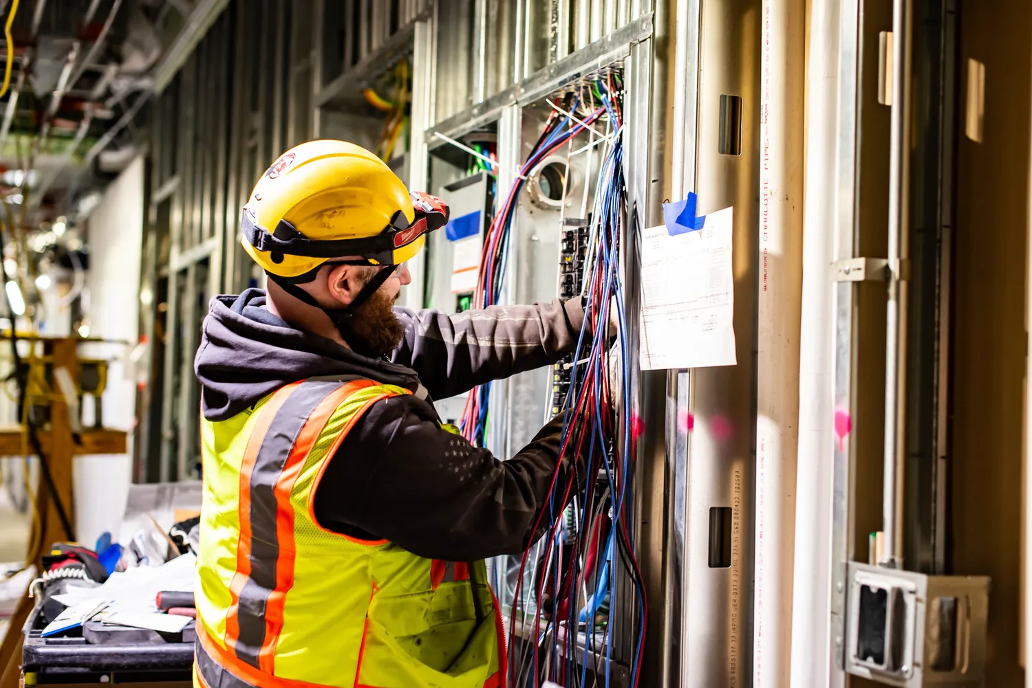 Electrician working on building wiring while wearing high-visibility safety gear