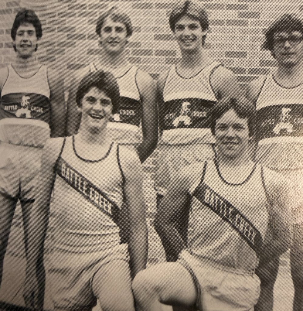 Battle Creek track & field squad — "BATTLE CREEK" sash jerseys, brick wall portrait