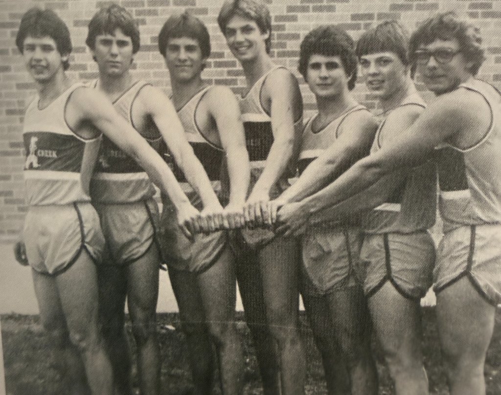 Braves track team — seven athletes united, hands joined before the meet
