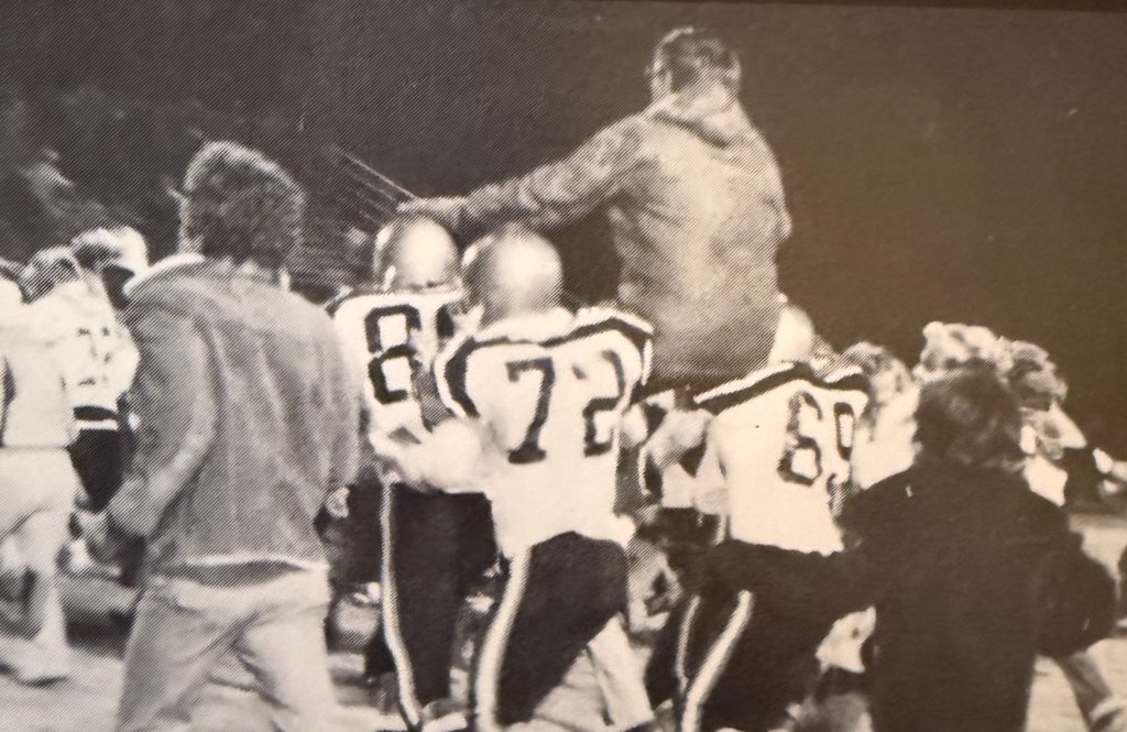Football sideline — jerseys 87, 72, 69 and the coach signals the play