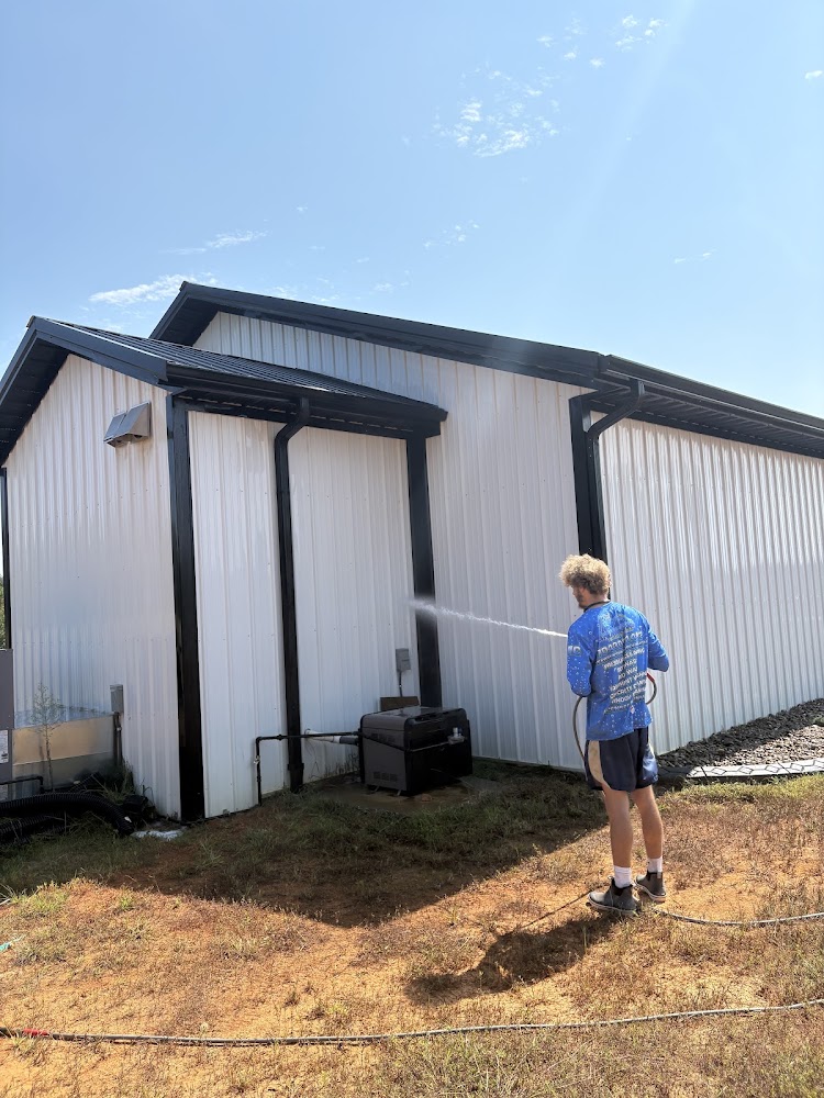 Technician pressure washing an industrial metal-sided building