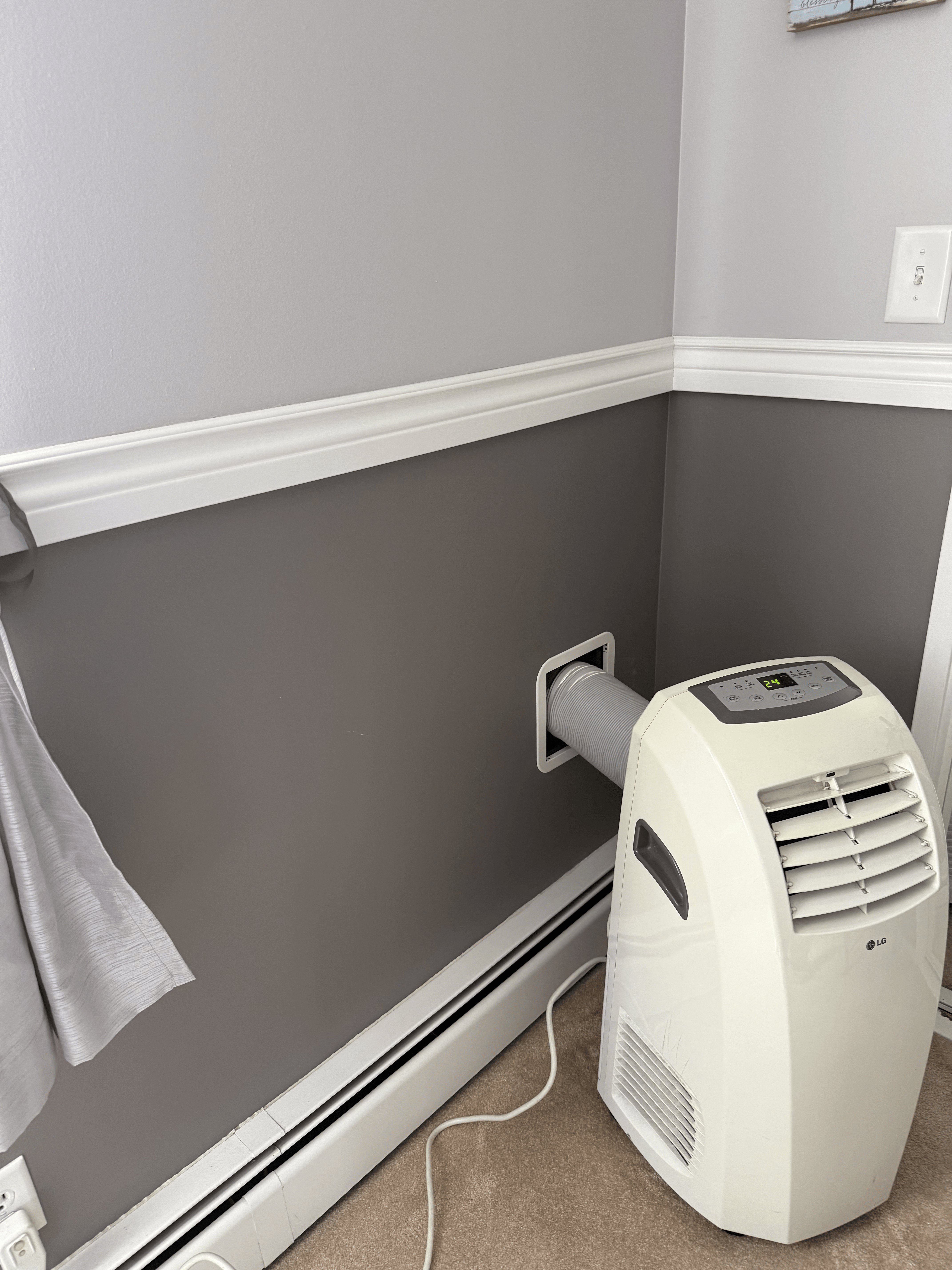 Portable AC exhaust hose connected to the Air Socket wall vent in a bedroom