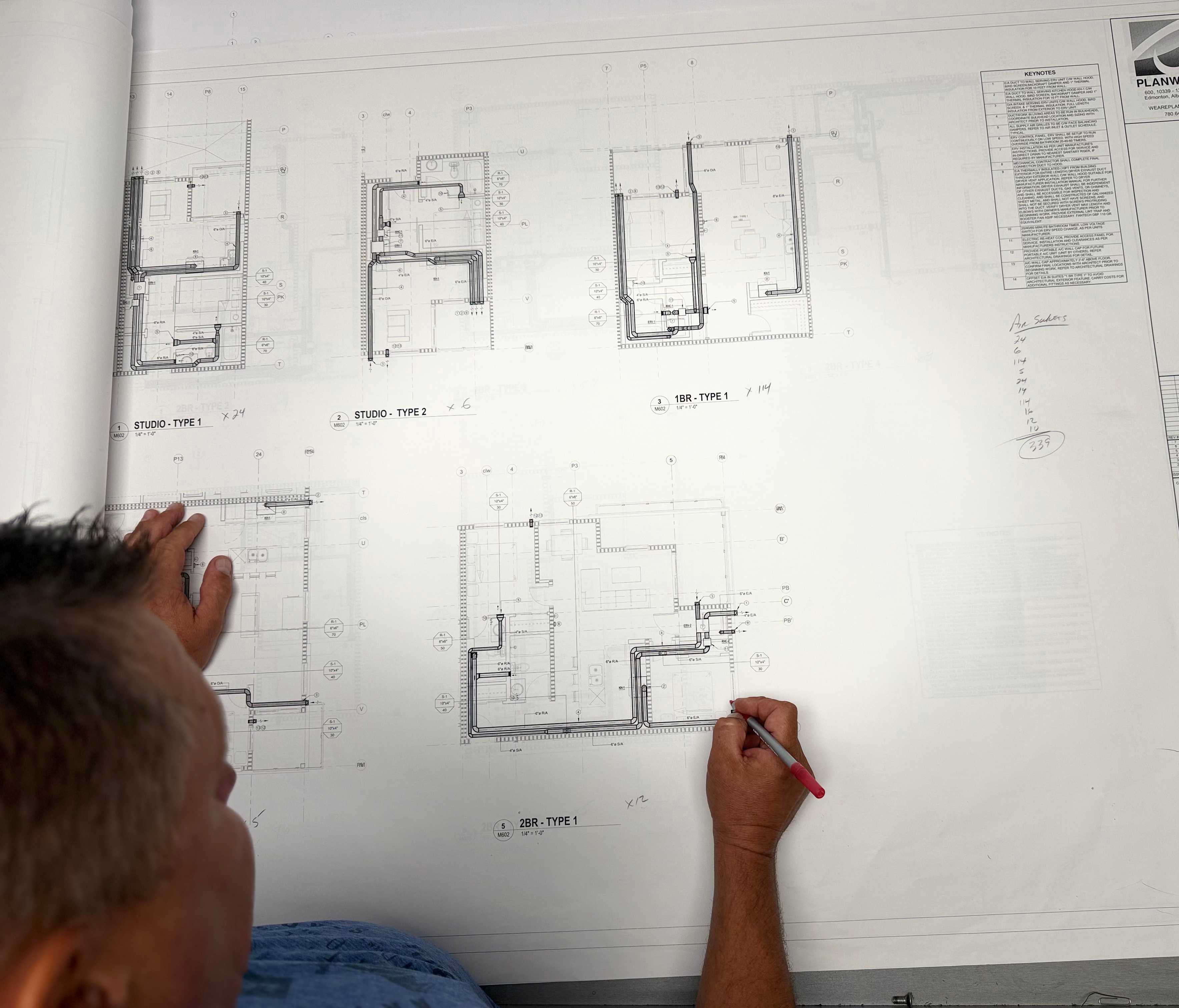 Engineer reviewing a multi-family HVAC blueprint, marking Air Socket venting details
