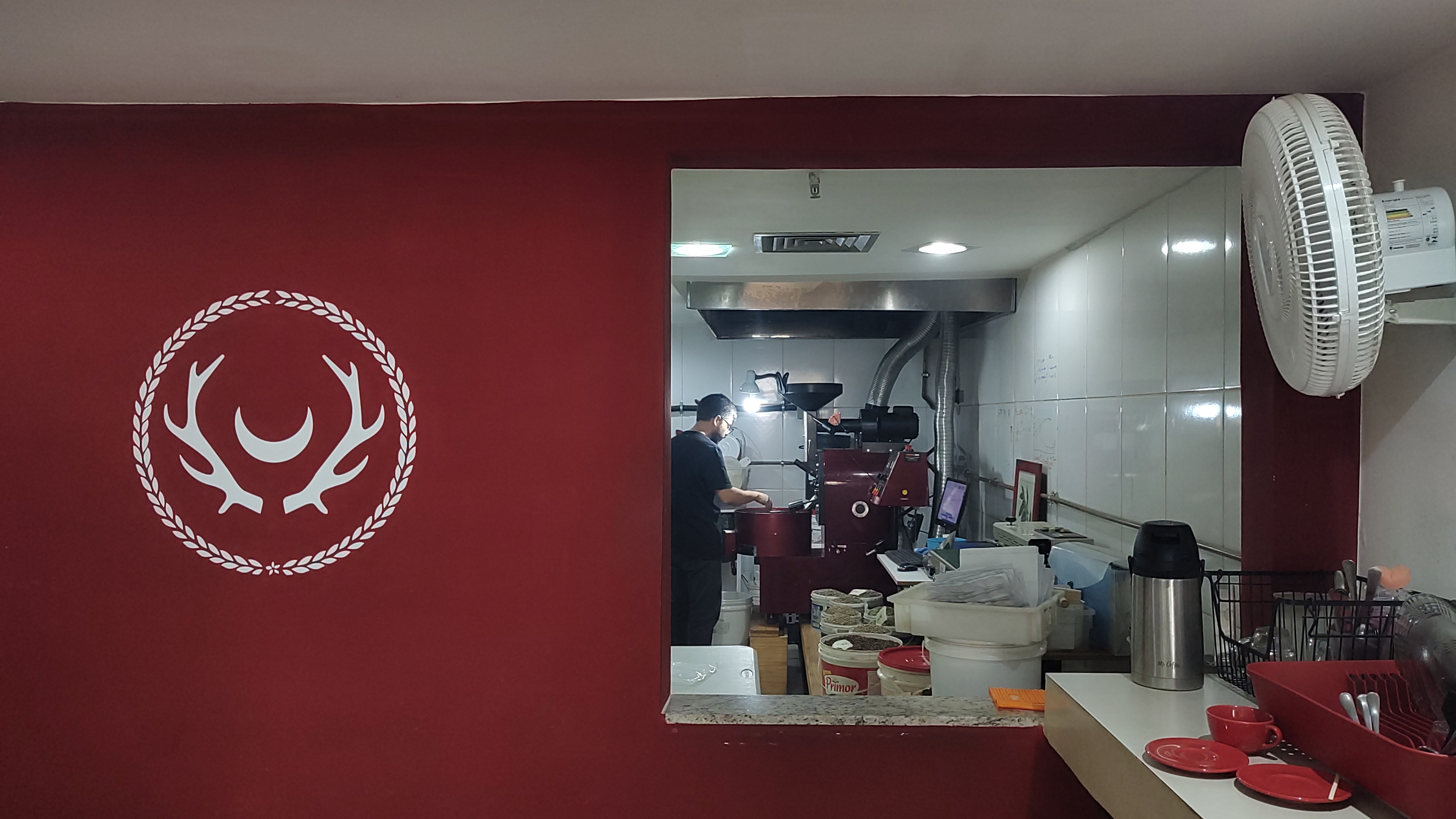 Logo da Artemis na parede da torrefação com equipe trabalhando ao fundo