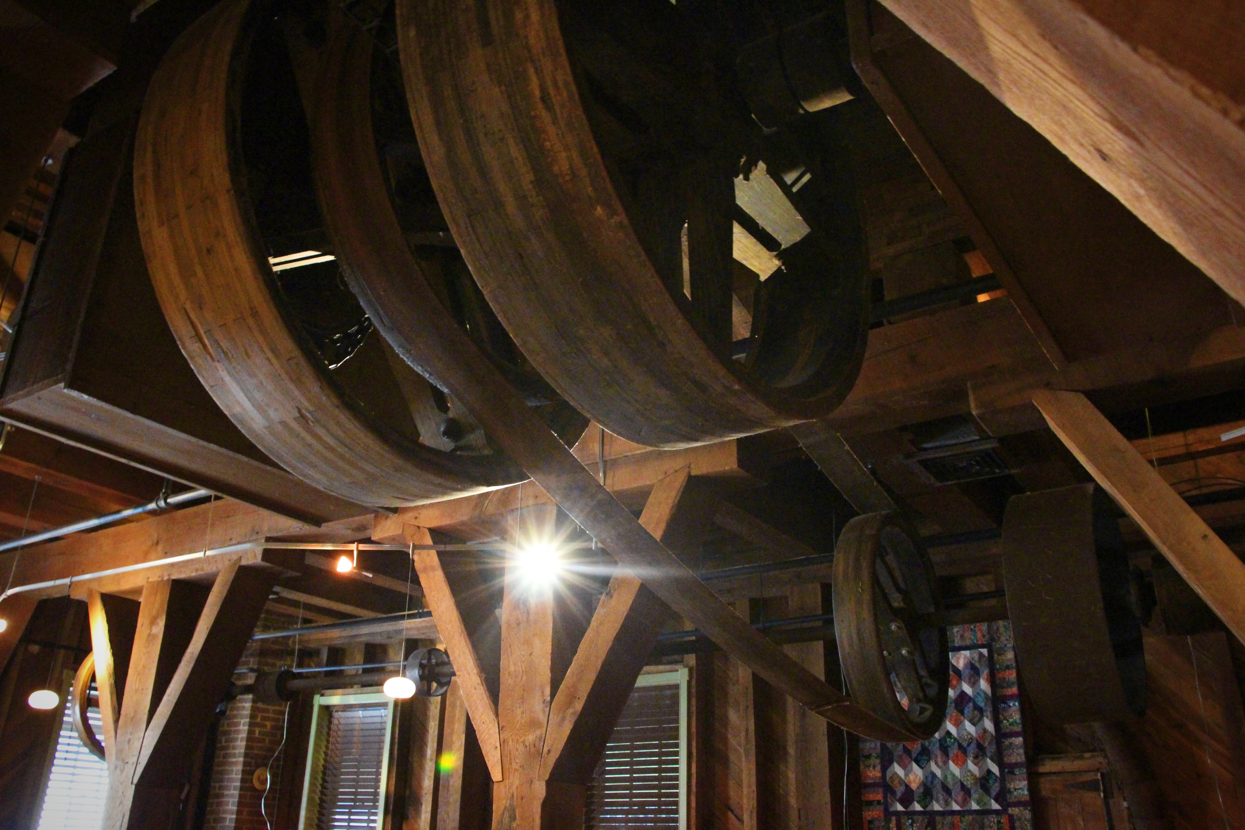 Belt-driven pulleys still hang from the rafters — the mill’s original machinery, preserved above the dining room like the bones of an older industry.