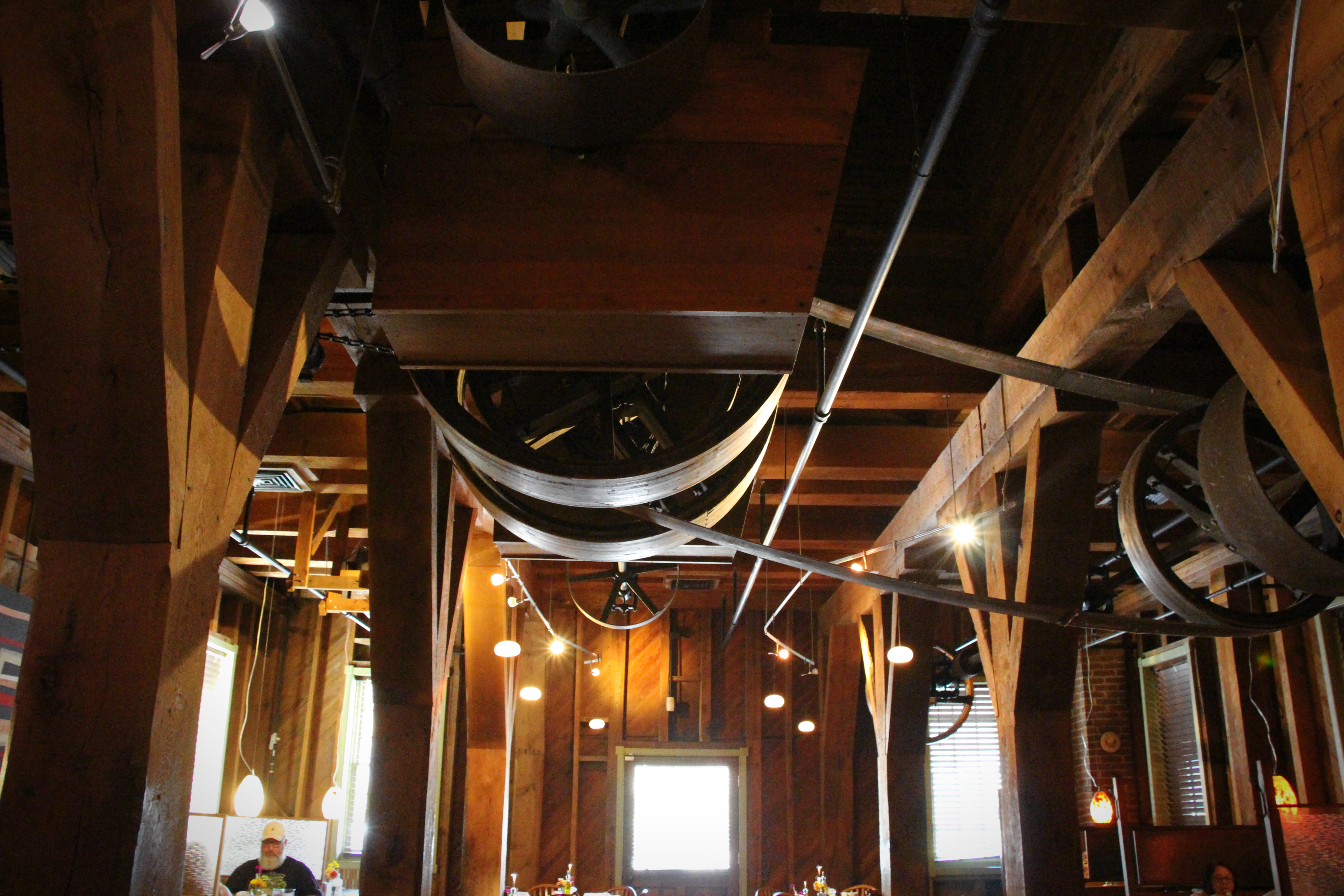 Looking up through the gears: the machinery that once ground the county’s grain now frames an evening service below.