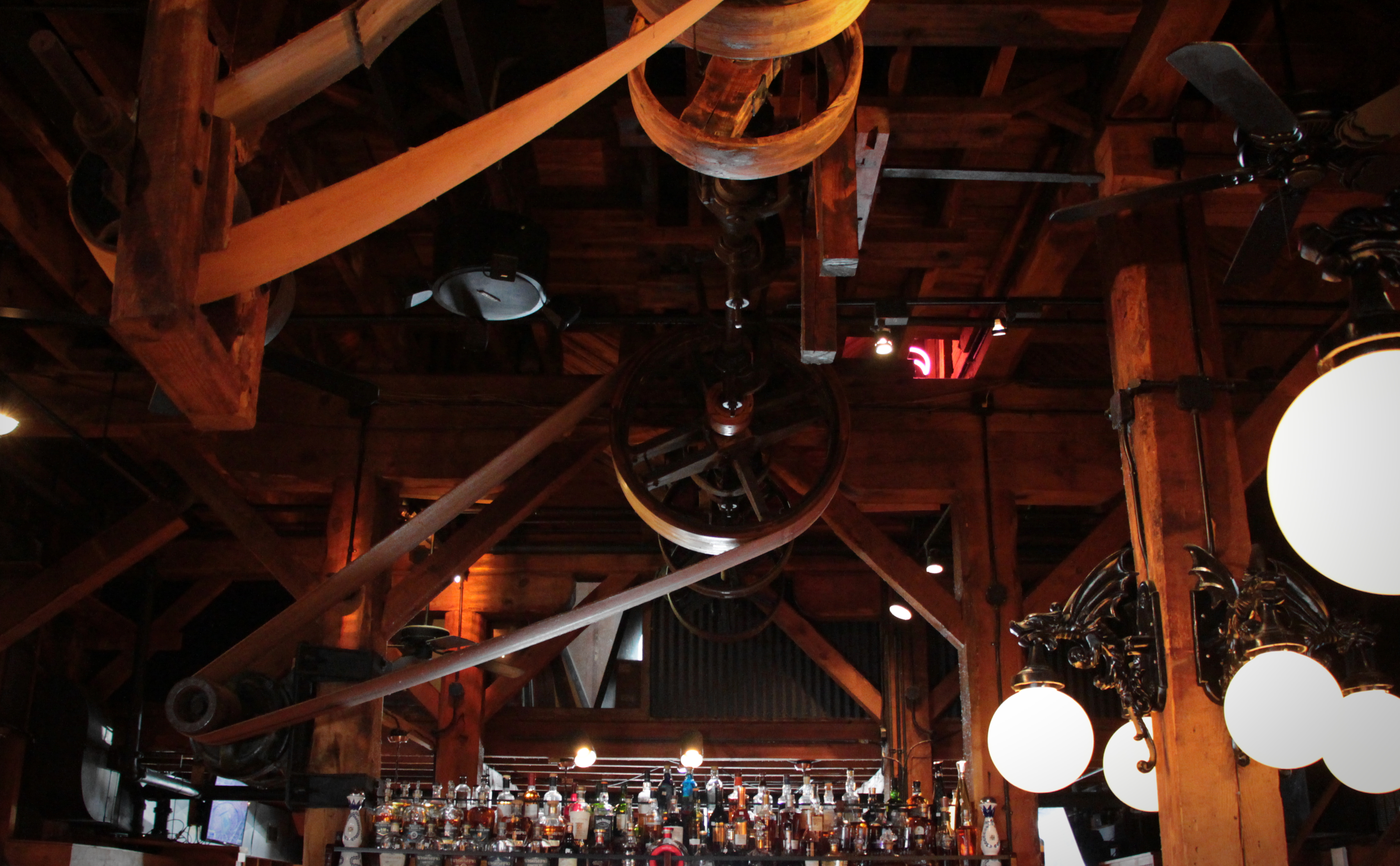 Inside Tuscarora, the original pulleys and drive belts remain suspended over the bar, lit by warm pendant lights.