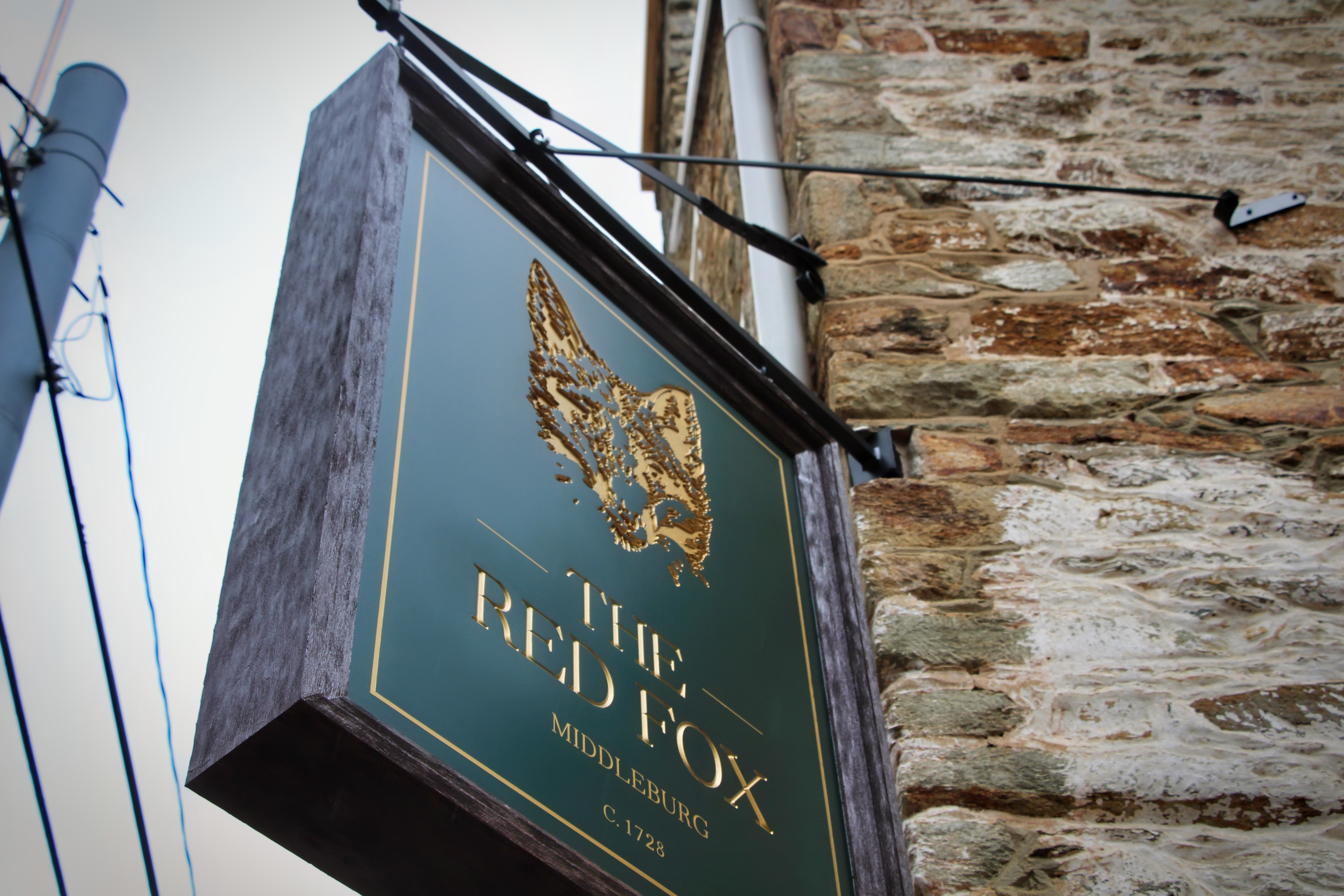 The inn’s sign: a gold fox, a green board, and a date older than the republic.