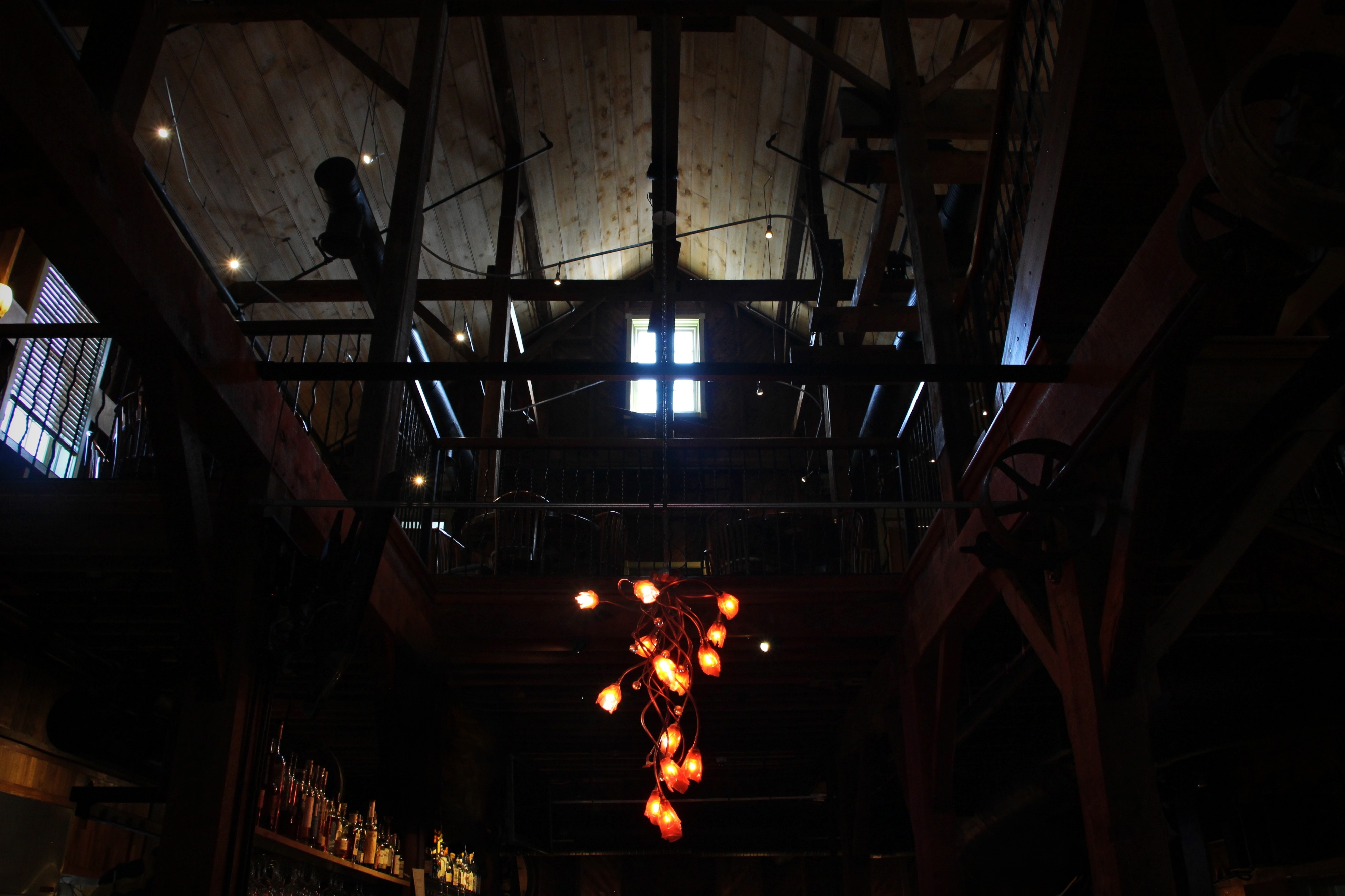 A floral chandelier presides over the open stairwell, where the mill’s upper gallery watches over the bar below.