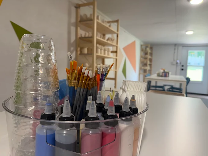 Art supply caddy with paintbrushes and paint bottles in the studio