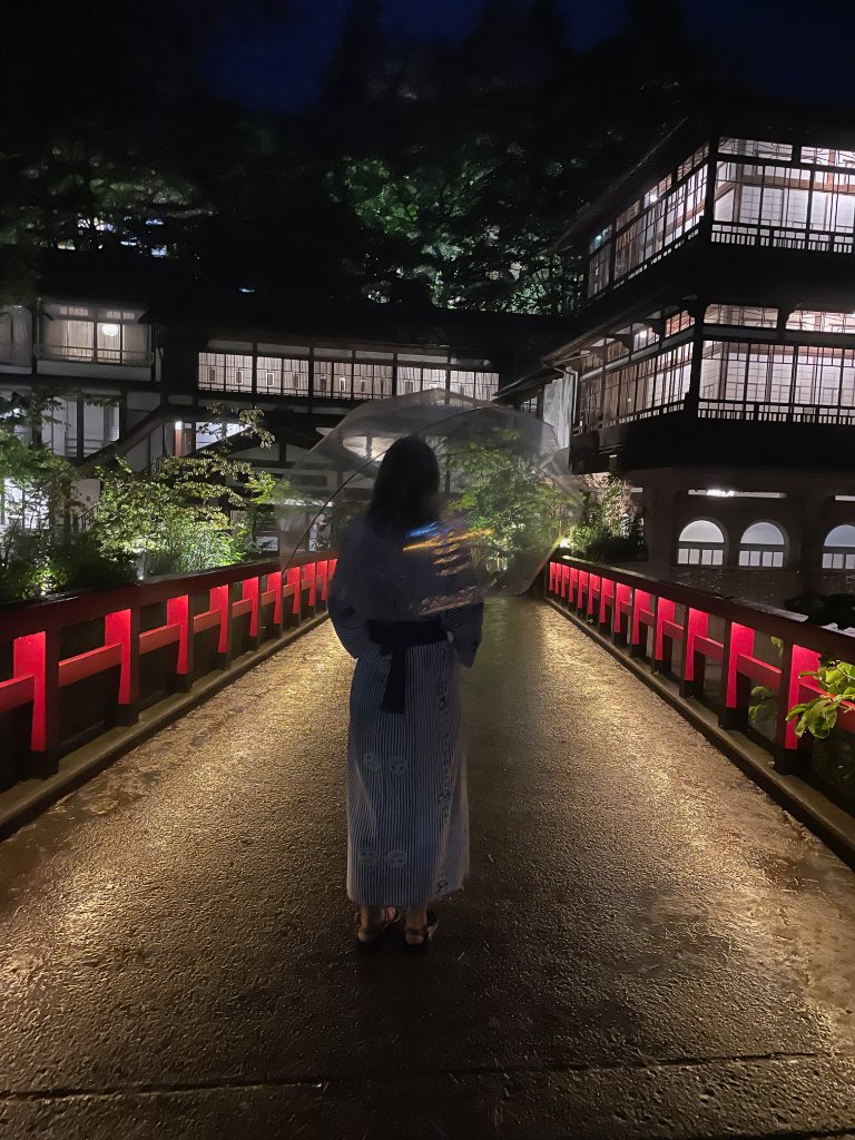 Woman in yukata on a bridge at a ryokan at night