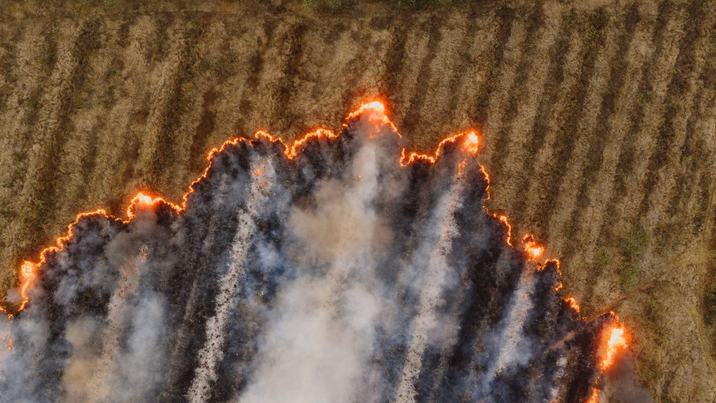 Aerial view of a wildfire advancing across arable land β drone intelligence is increasingly key to wildfire command.