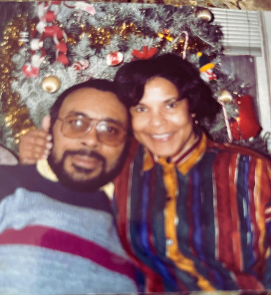 Kenneth and Regina cheek to cheek in front of the Christmas tree