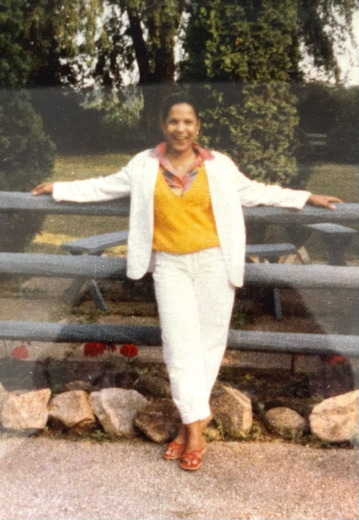 Regina L. Murrey outdoors, arms wide open, white blazer, full of joy