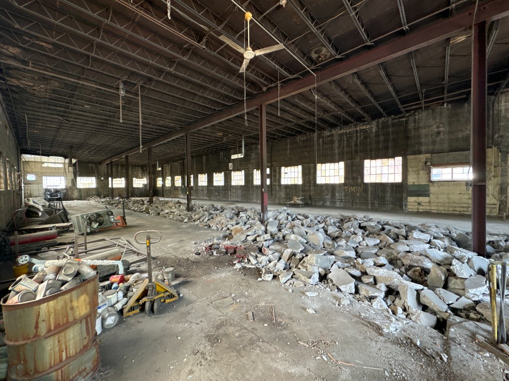 Wide interior of the 930 Sidney Street warehouse post-demolition, steel columns exposed, daylight flooding through warehouse windows.