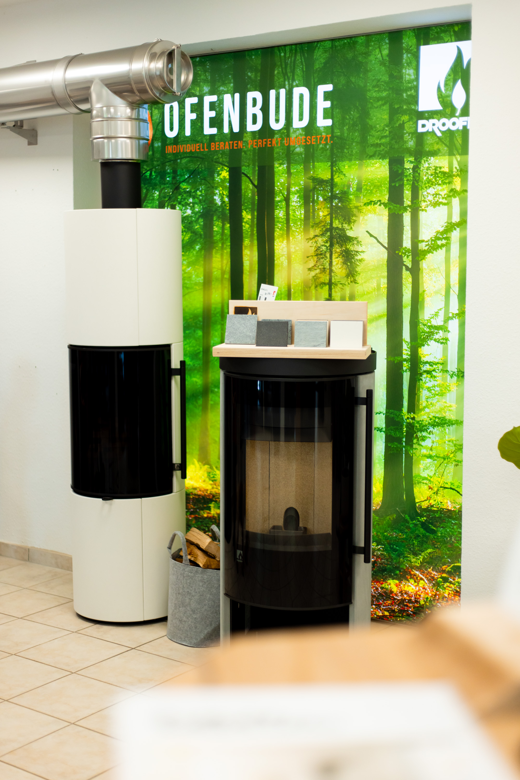 ofenbude_showroom_beratung_ahlen – Beratungstheke im Showroom mit brennenden Ausstellungsöfen der Ofenbude