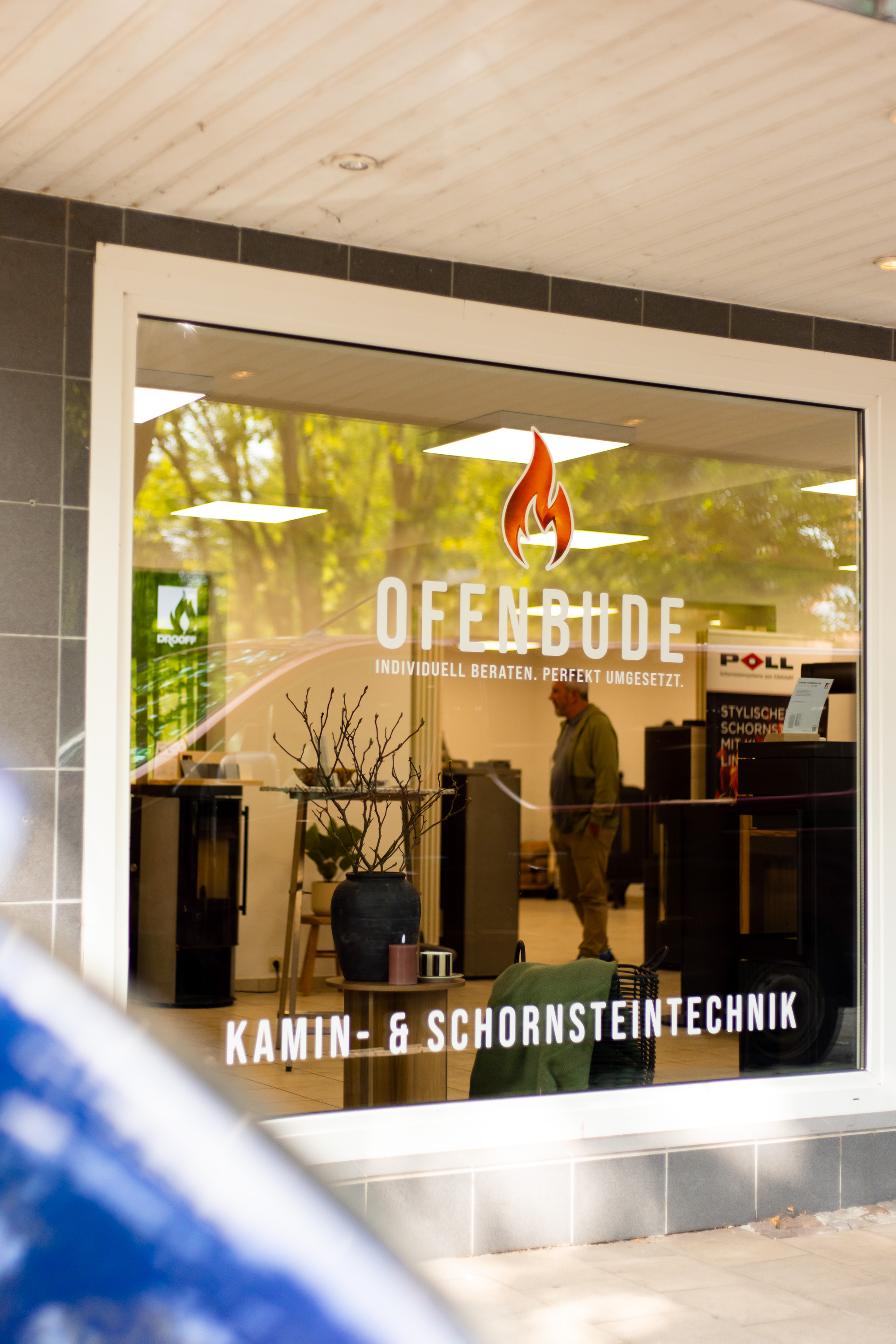 ofenbude_aussenansicht_ahlen – Frontansicht des Ofenbude-Ladengeschäfts in Ahlen mit großflächiger Schaufensterfront und Kaminöfen