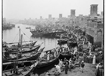 Historia Dubaju: drewniane dhowy i dawne domy kupców z wieżami wiatrowymi nad Dubai Creek w epoce pereł