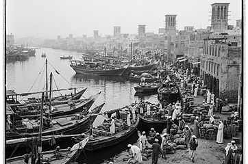 Historia Dubaju: drewniane dhowy i dawne domy kupców z wieżami wiatrowymi nad Dubai Creek w epoce pereł