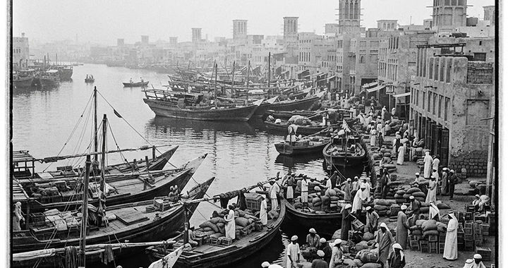 Historia Dubaju: drewniane dhowy i dawne domy kupców z wieżami wiatrowymi nad Dubai Creek w epoce pereł