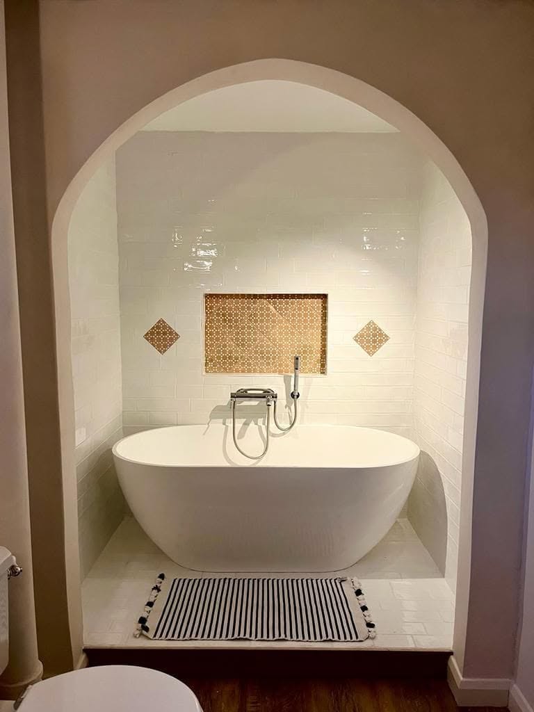 Finished bathroom with a freestanding tub set in an arched subway-tiled alcove, renovated by Timmins Landscapes