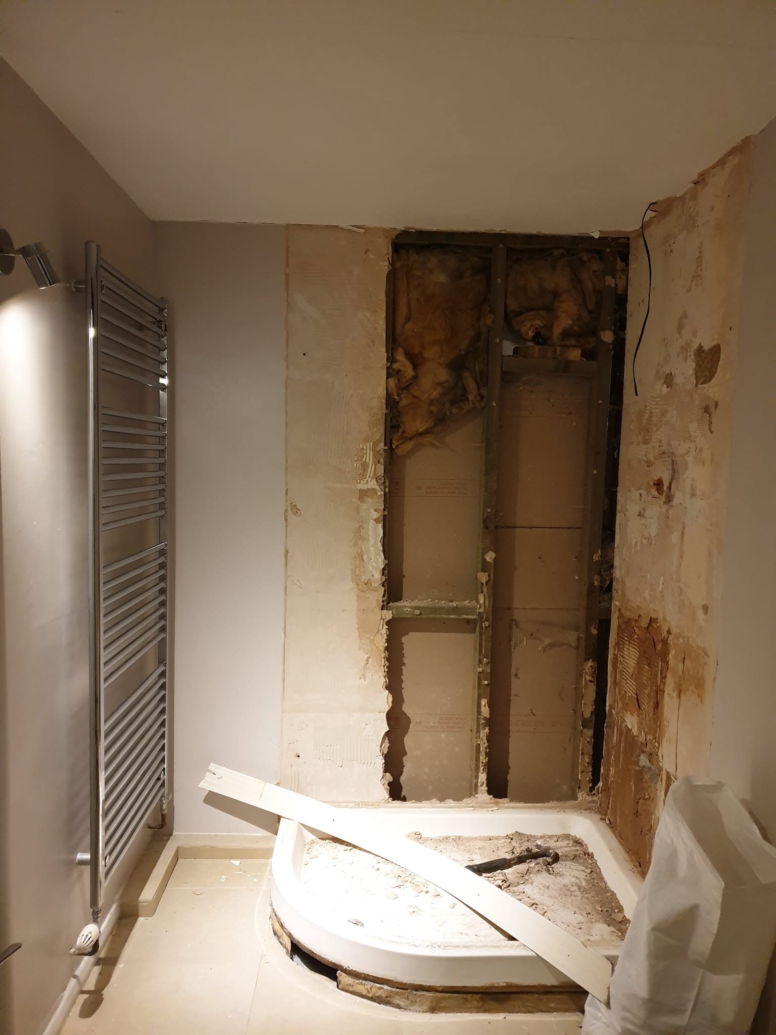 Bathroom mid-renovation, with exposed wall studs and a shower tray under construction
