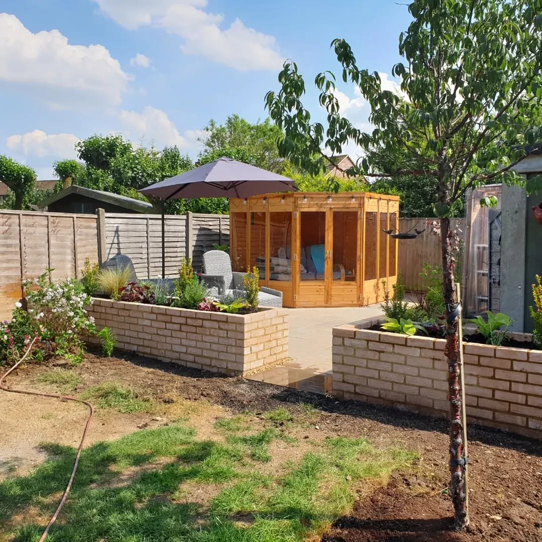 Garden after transformation with a new patio, raised brick beds and a timber summerhouse by Timmins Landscapes