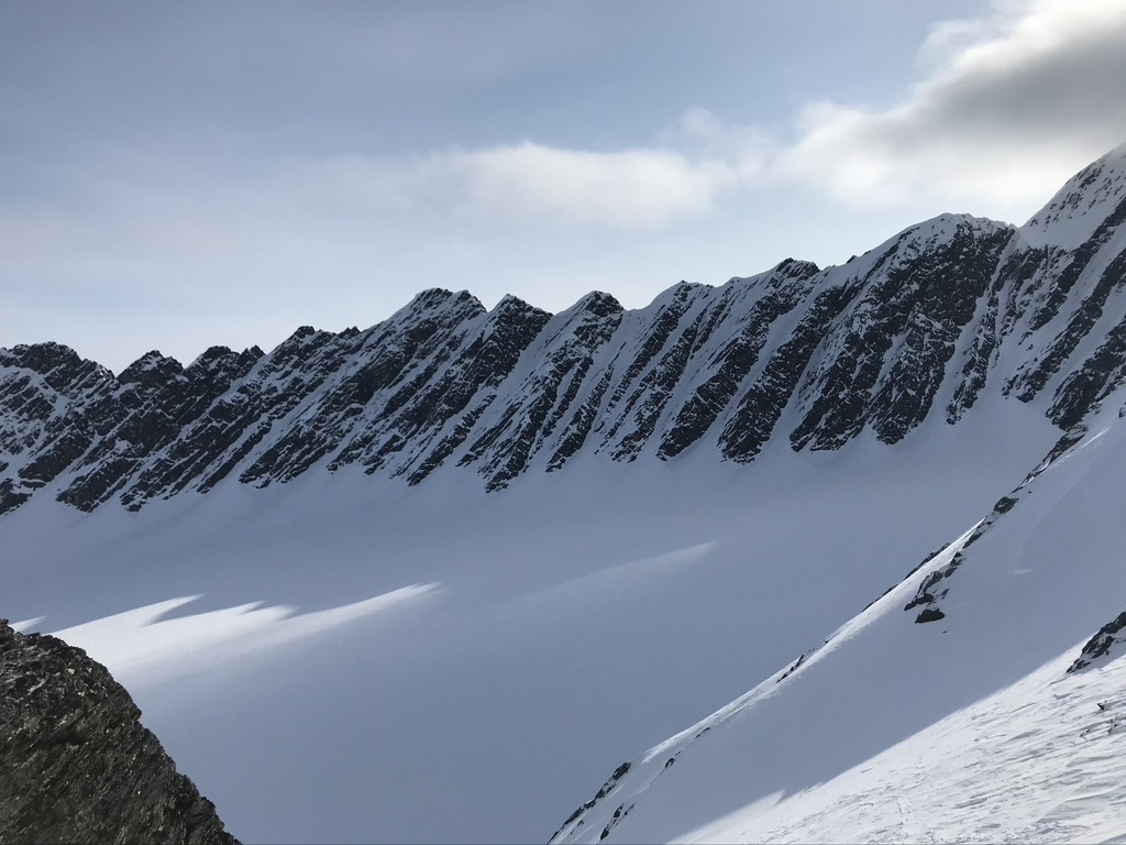 Ski tourers ascending glaciated terrain toward Svalbard summit with sea views